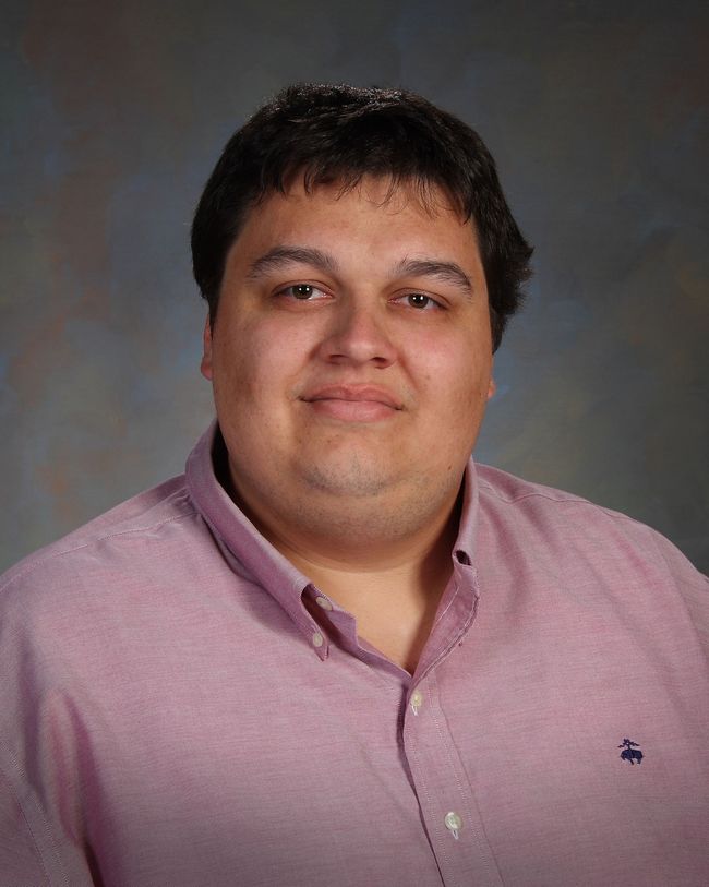 Portrait of a person in a pink button-up shirt against a gray studio backdrop
