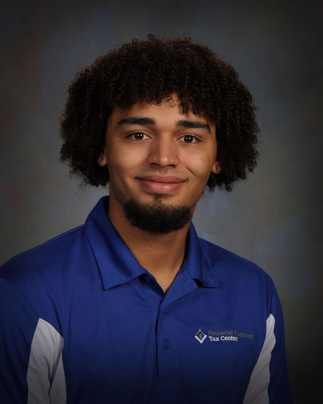 Studio portrait of a smiling person in a blue collared shirt with gray sleeve accents against a gray backdrop