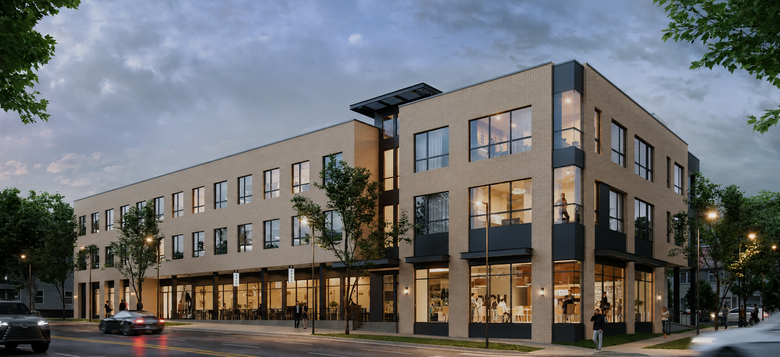 Modern three-story brick apartment building on a street corner at dusk, with lit windows and ground-floor storefronts