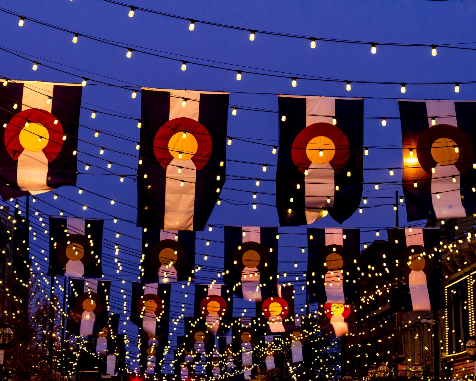 Festive street display with hanging lights and repeated illustrated banners against a twilight sky
