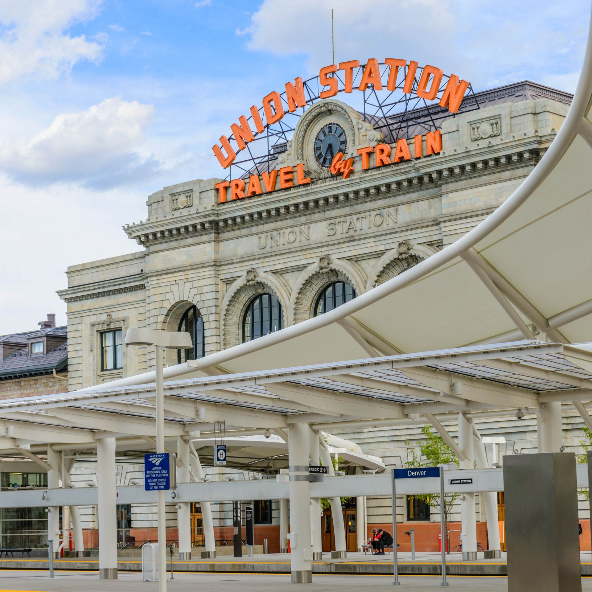 Union Station facade with orange sign and white canopy under a partly cloudy sky