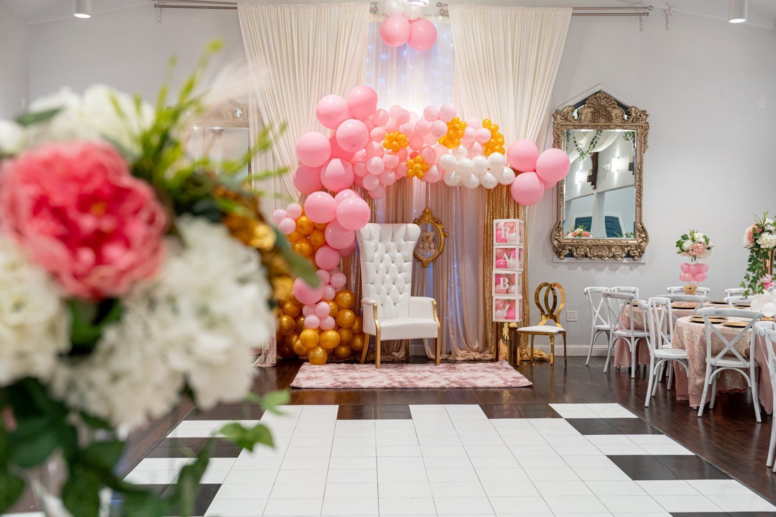 a room decorated with pink and gold balloons and flowers for a baby shower .