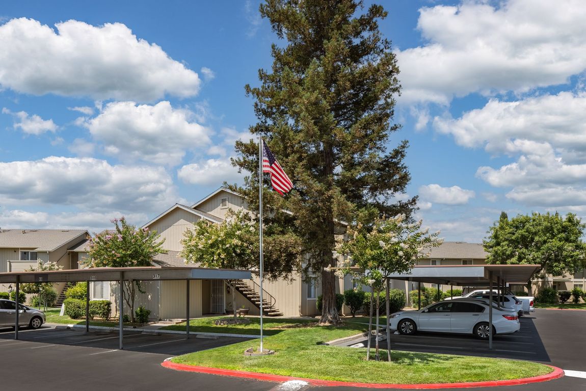 Apartment building with covered parking and American flag on a sunny day.
