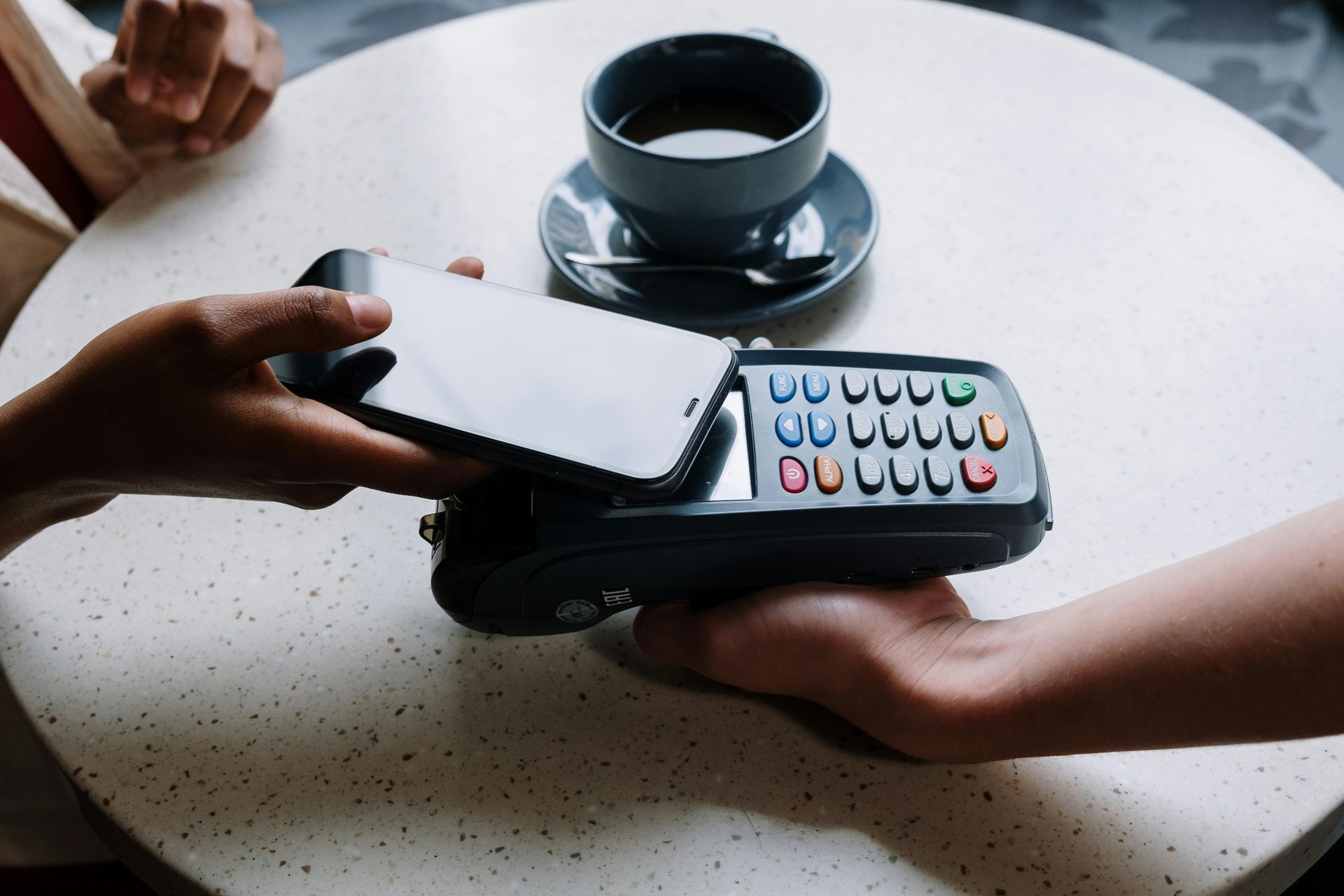 A person is using a phone to pay for a cup of coffee.