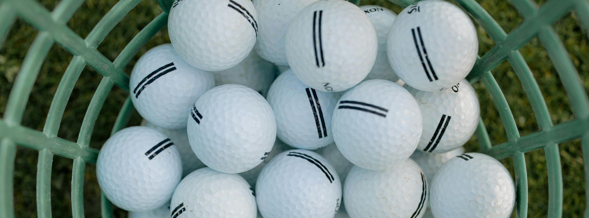 A bunch of white golf balls in a green basket