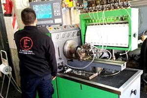 Mecánico trabajando en una máquina de prueba de motores, vestido con camisa negra, en el interior con el equipo.