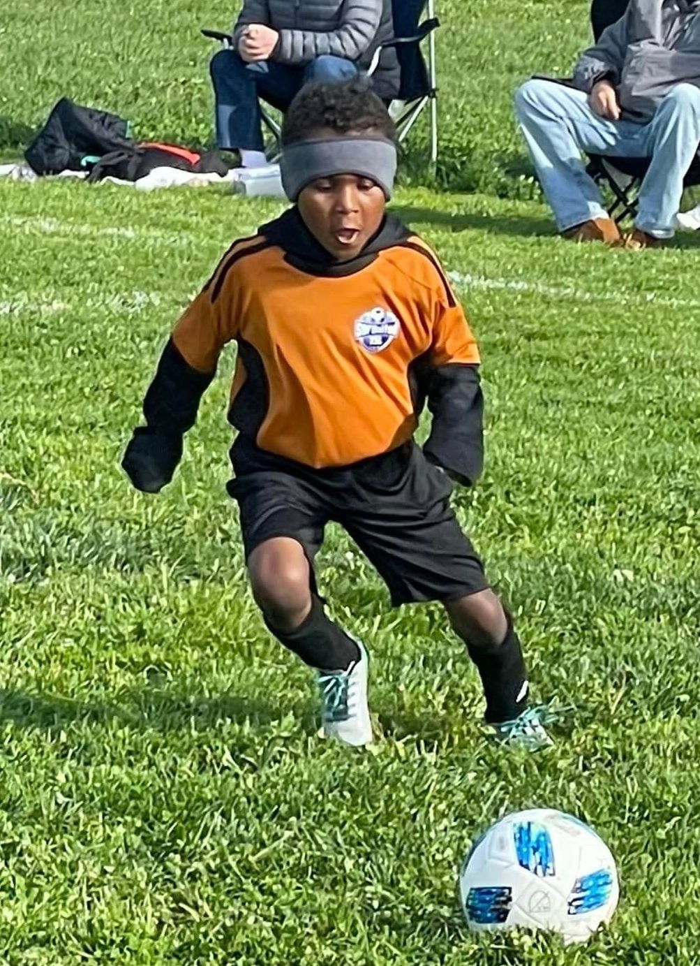 A young boy is kicking a soccer ball on a field.