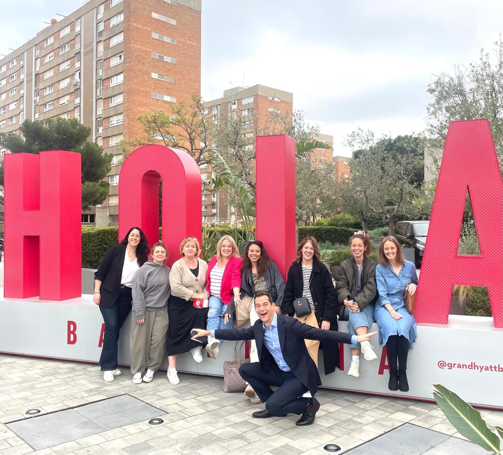 Group of people pose by large, red 