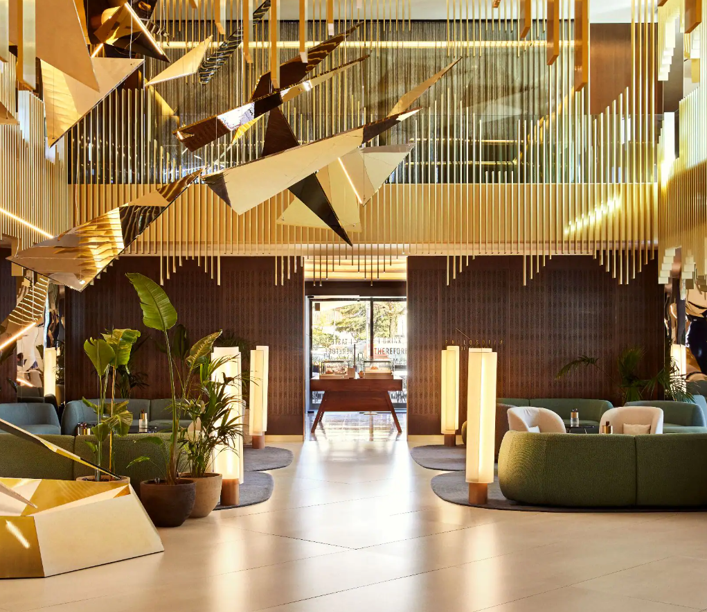 Lobby with green seating, gold accents, and a decorative ceiling installation.
