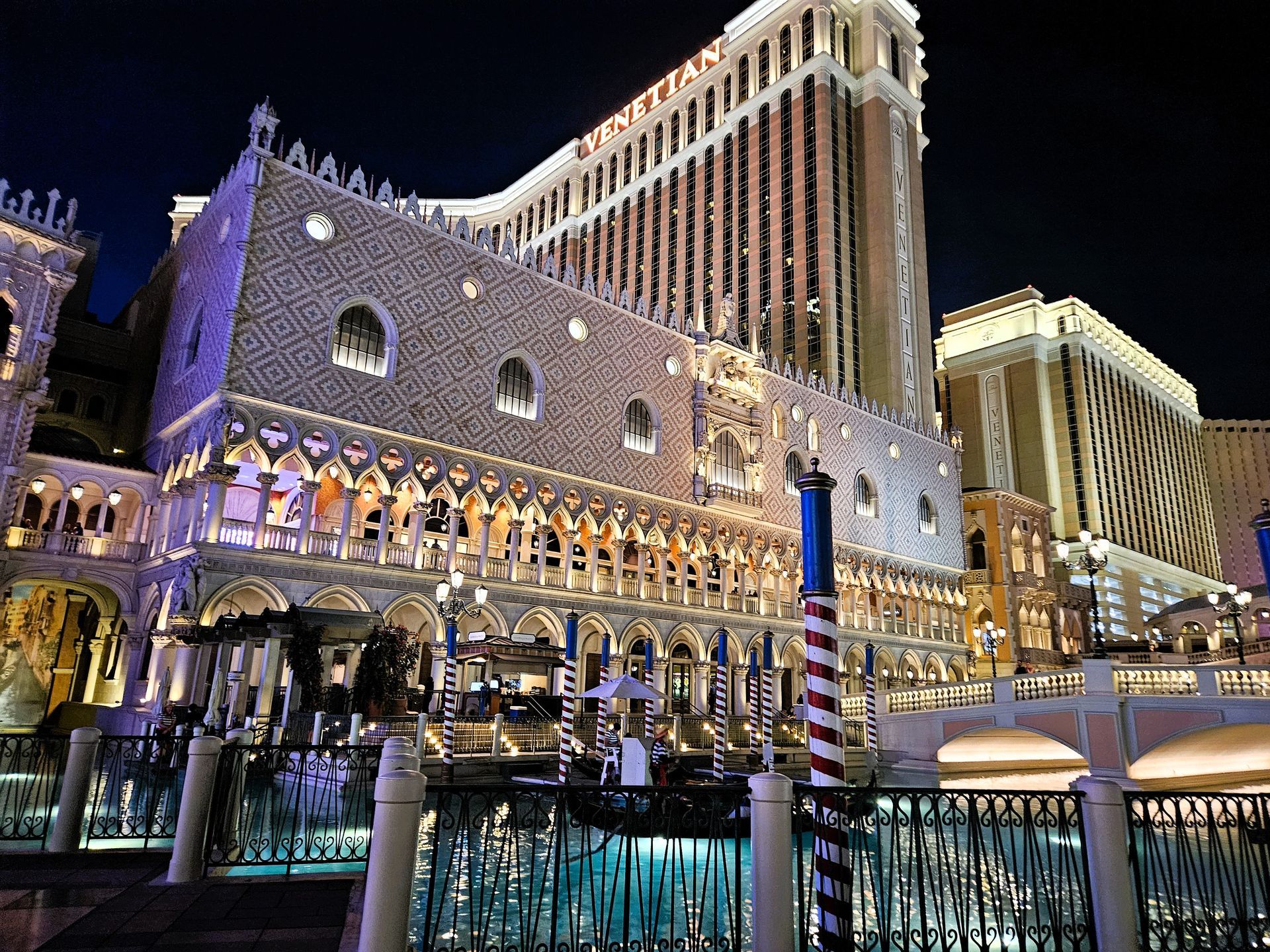 The Venetian hotel in Las Vegas at night; detailed architecture illuminated, with gondolas and water in front.