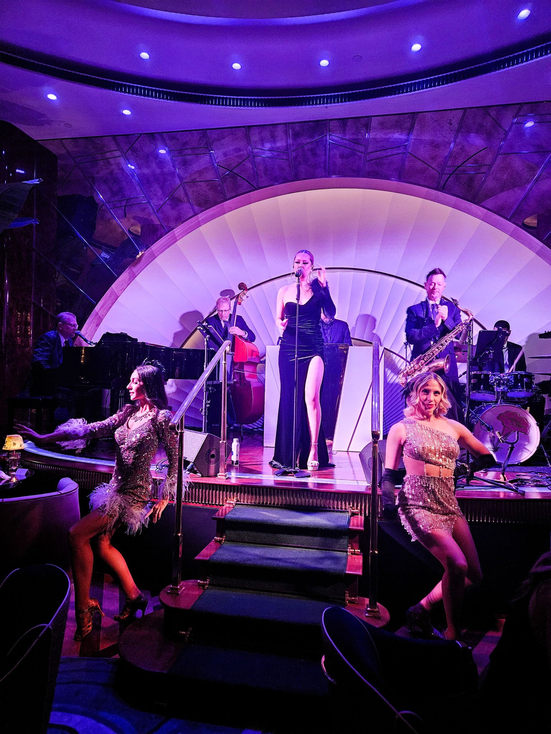 Band performing on stage with two dancers. Stage lit in purple.