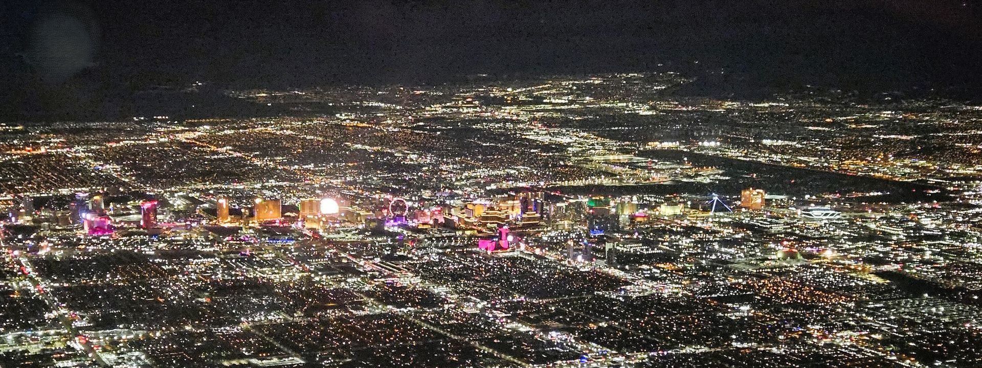 Nighttime aerial view of a brightly lit city with colorful buildings and scattered lights.