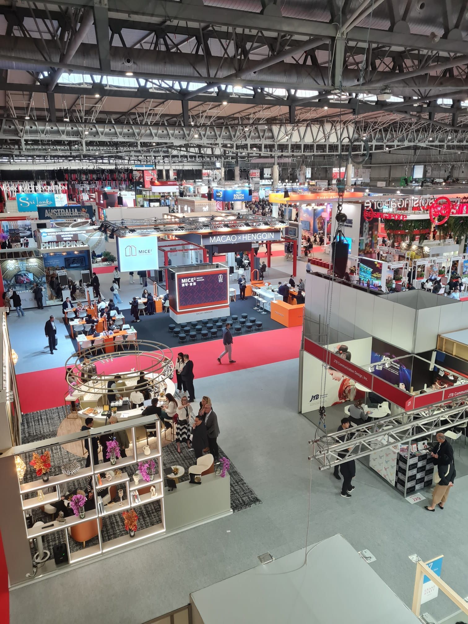 Large convention hall filled with booths and attendees; many people milling about.