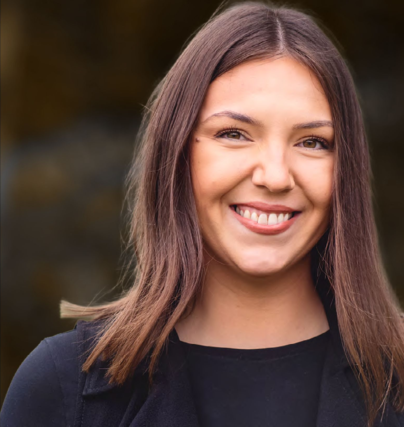 Woman with brown hair smiling, outdoors, wearing black clothing.