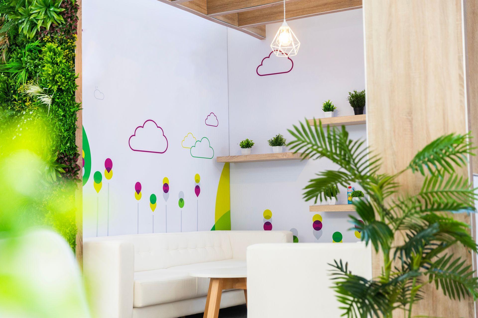 Cozy office corner with white sofa, plant wall, floating shelves with plants, and cloud decals.