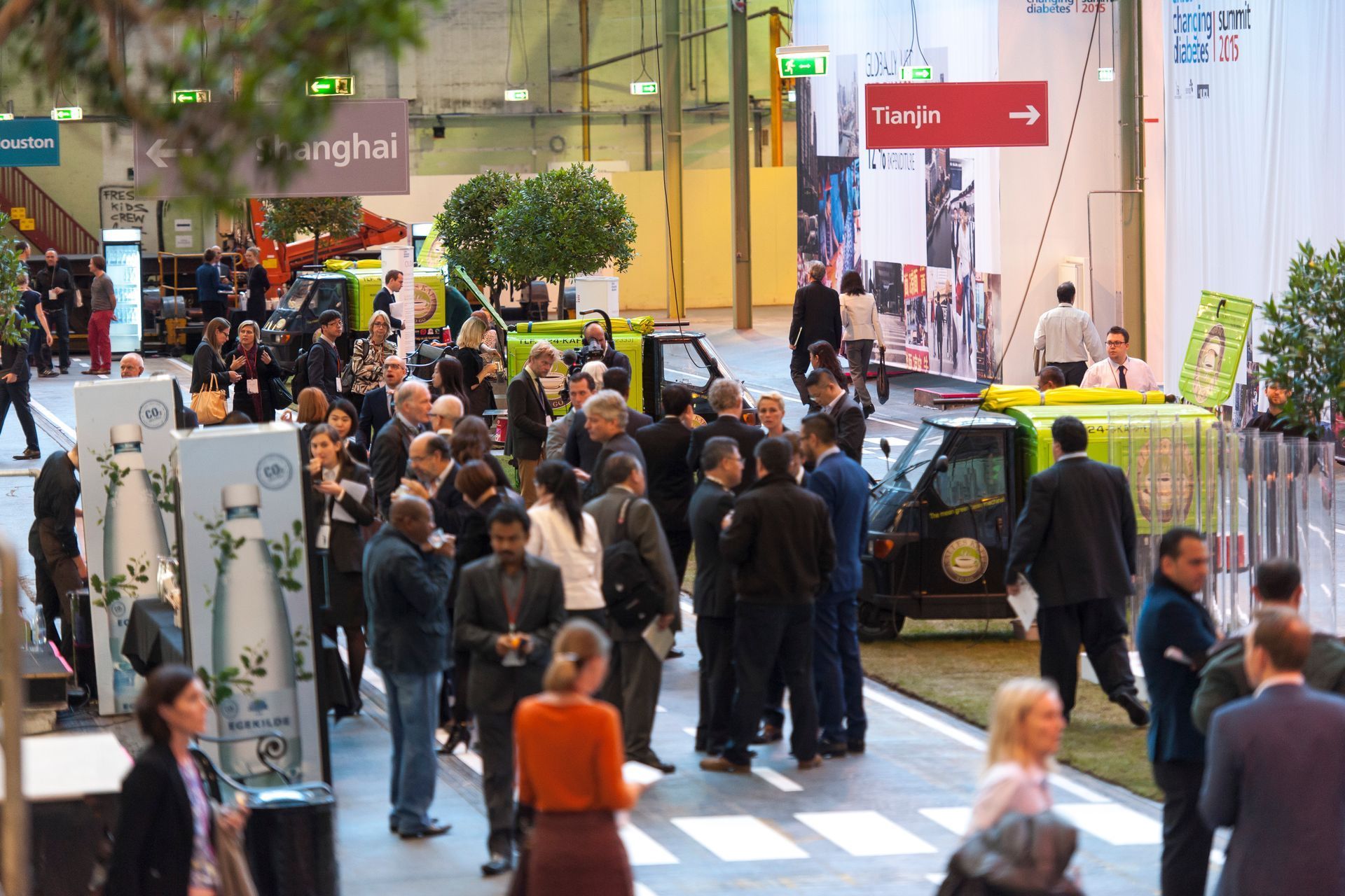 Crowded trade show aisle with people mingling around booths and displays
