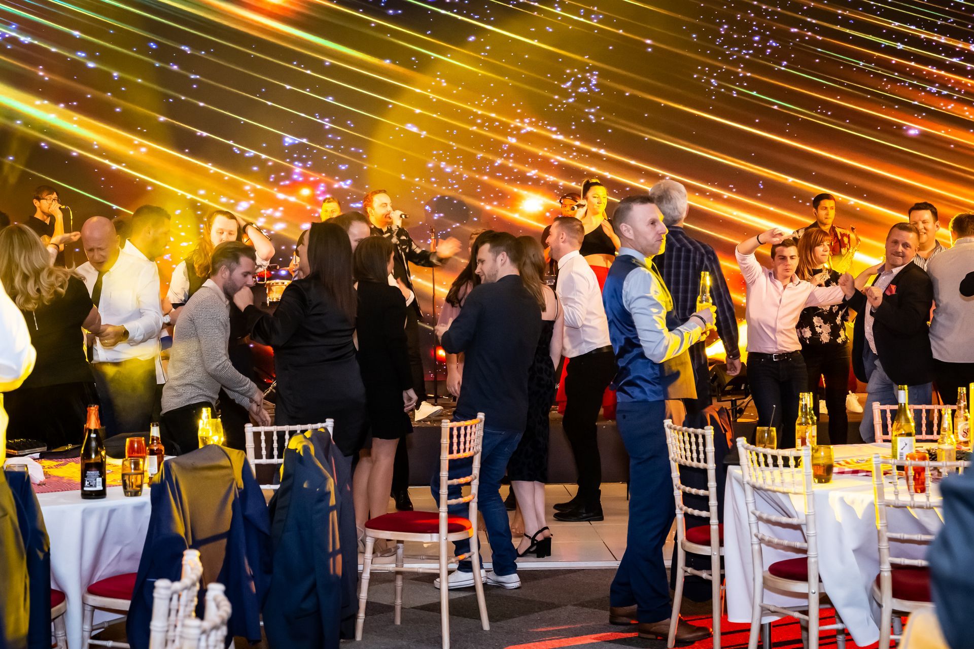 People dancing and celebrating at a gala or party with lights and tables.