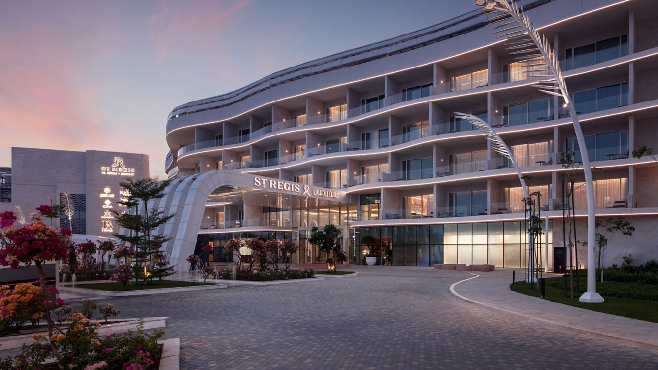 Hotel entrance with a curved facade and a cloudy twilight sky.