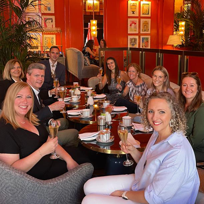 Group of people in a red-walled room, toasting with champagne.