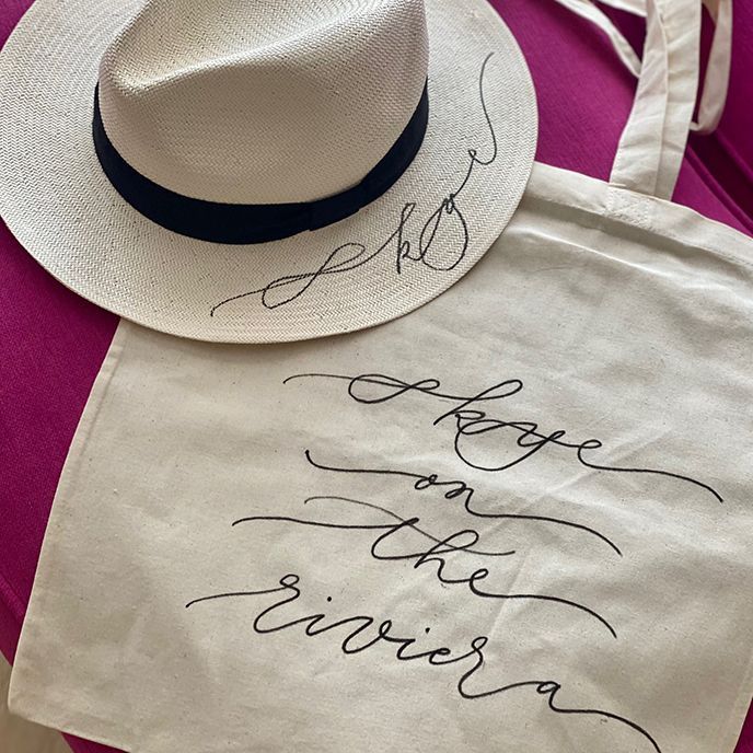White hat and tote bag with handwritten cursive script: