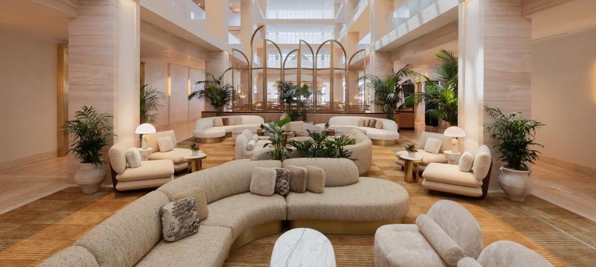 Spacious hotel lobby with seating areas, neutral colors, and large windows.