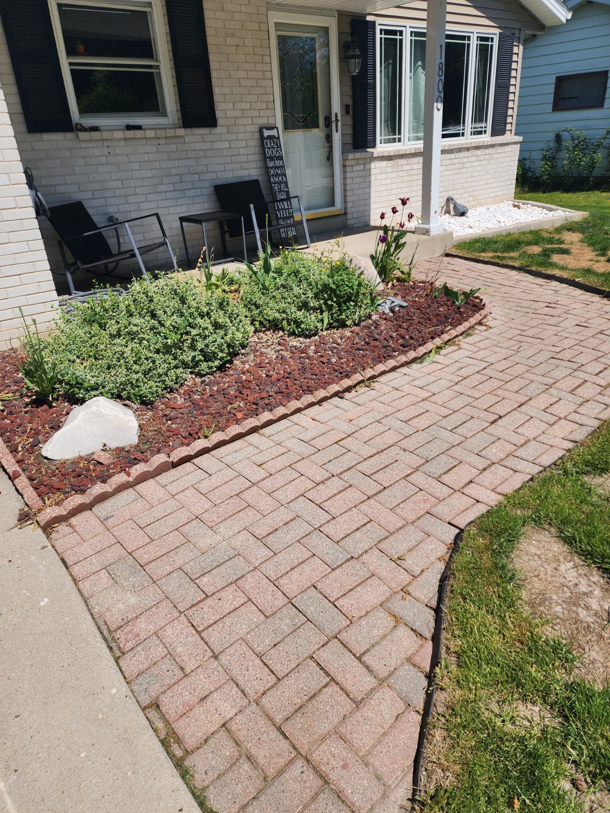 Stone retaining wall with layered gray rocks and a gravel base in sunlight