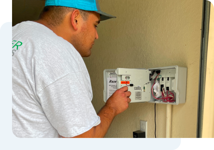 A man is working on an electrical box on a wall.