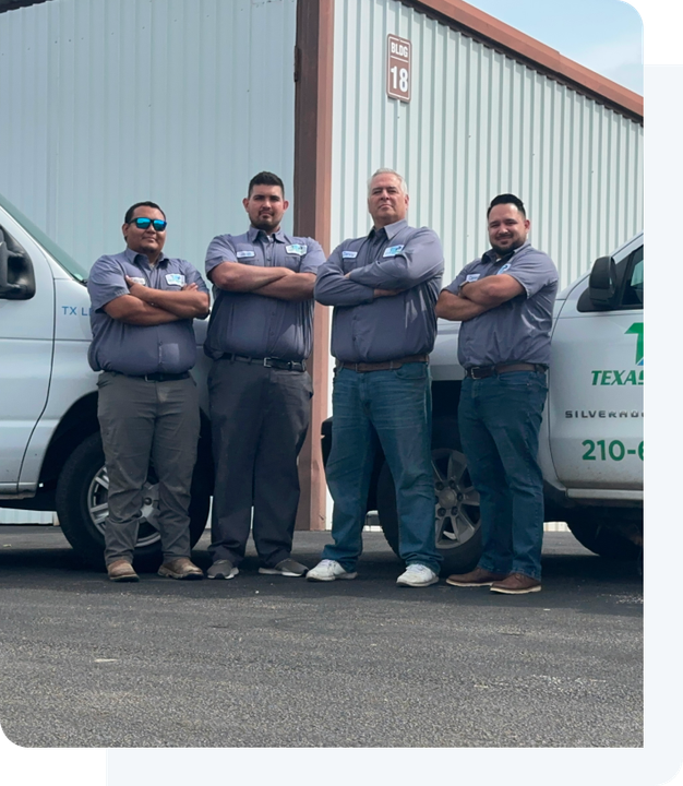 A team of men posing for a picture in front of Texas Sprinkler Pro's trucks.