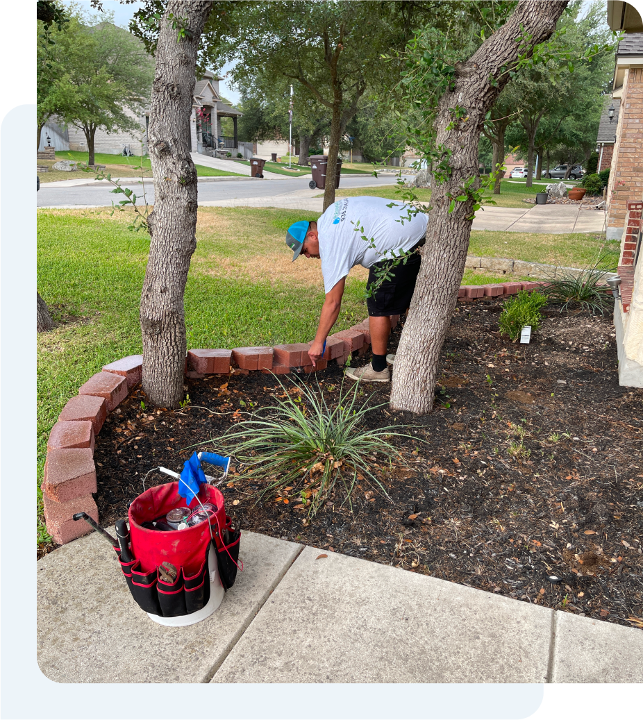 A man removing debris from a yard while doing water sprinkler maintenance.