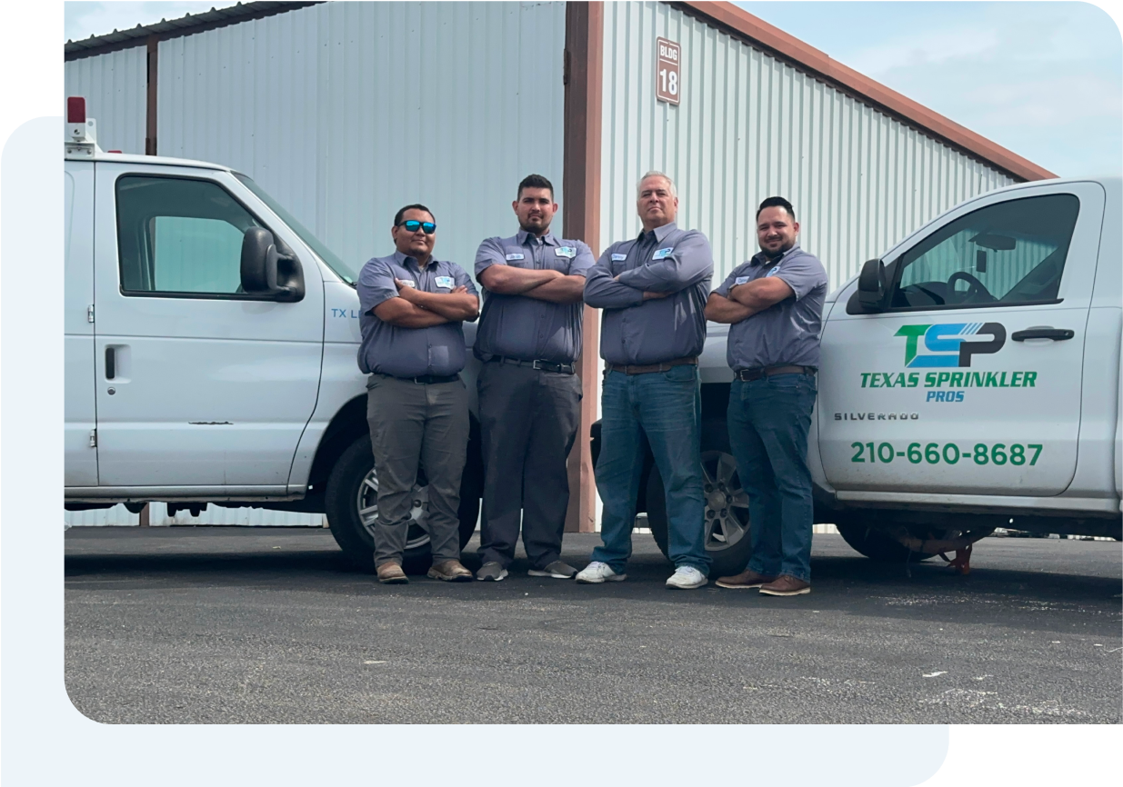 A team of men posing for a picture in front of Texas Sprinkler Pro's trucks.