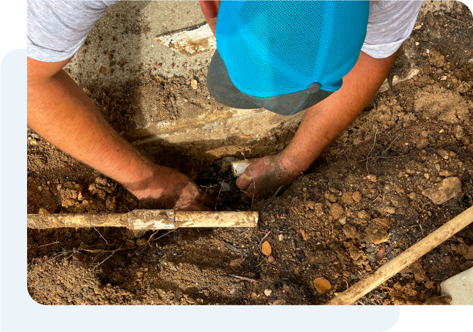 A man is working on a pipe in the dirt.