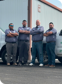 A team of men posing for a picture in front of Texas Sprinkler Pro's trucks.