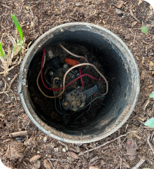 Exposed wires in a yard to reveal a valve malfunction in a water sprinkler system.