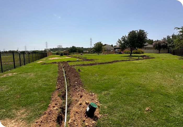 A hose is laying in the middle of a grassy field for a water conservation sprinkler system.