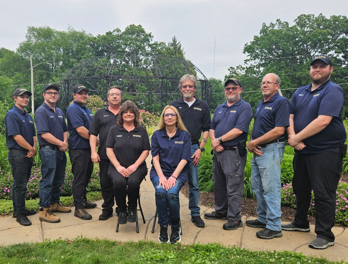 Group of uniformed police officers and staff posing outdoors on a cloudy day; one woman seated in front.