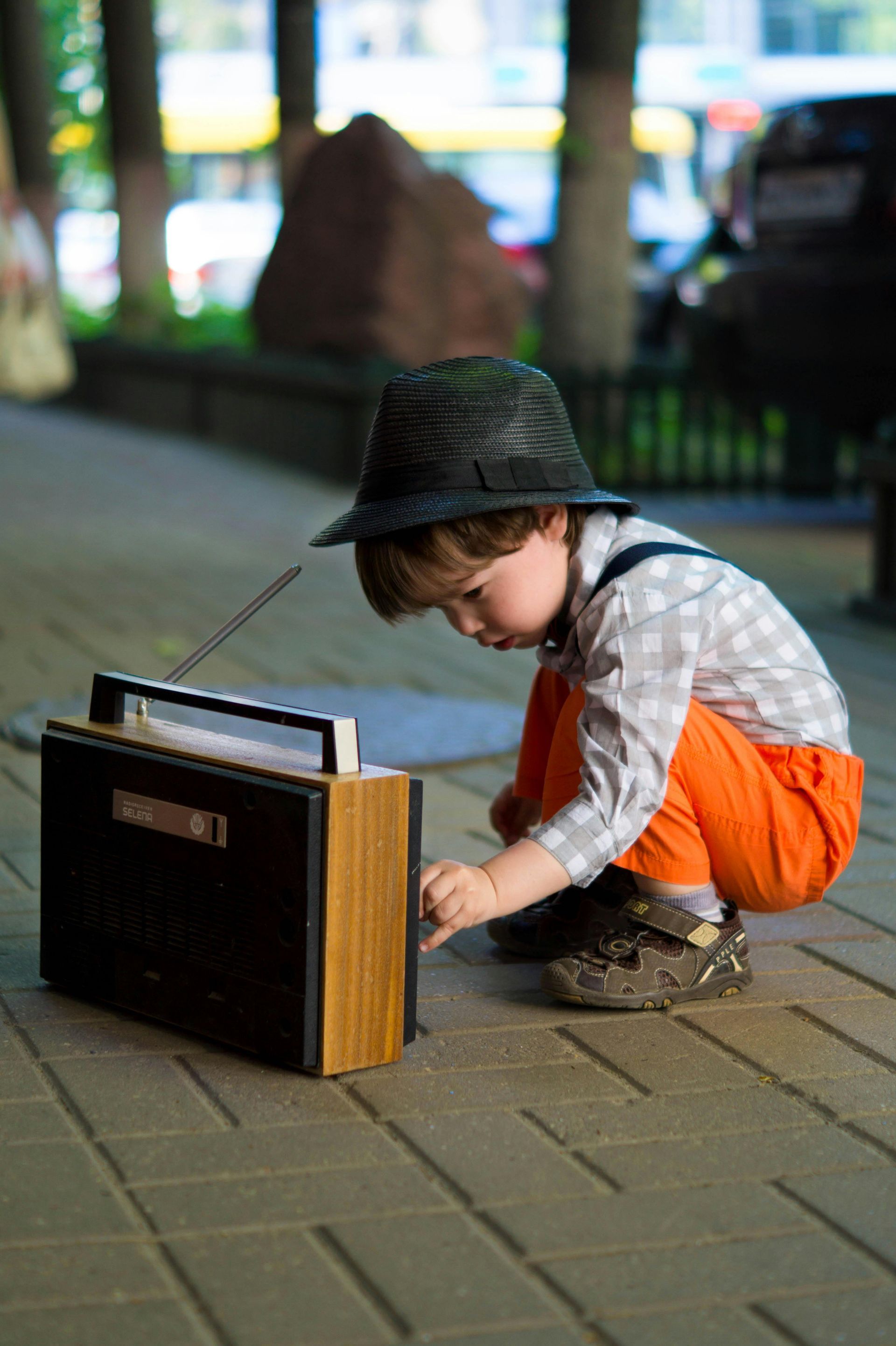Um garotinho está brincando com um rádio na calçada