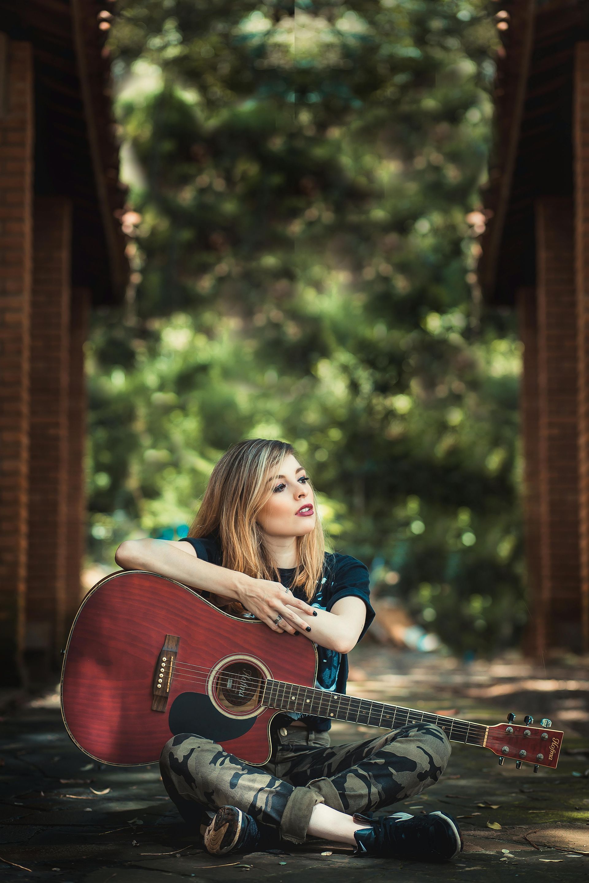 Uma mulher está sentada no chão segurando uma guitarra vermelha.