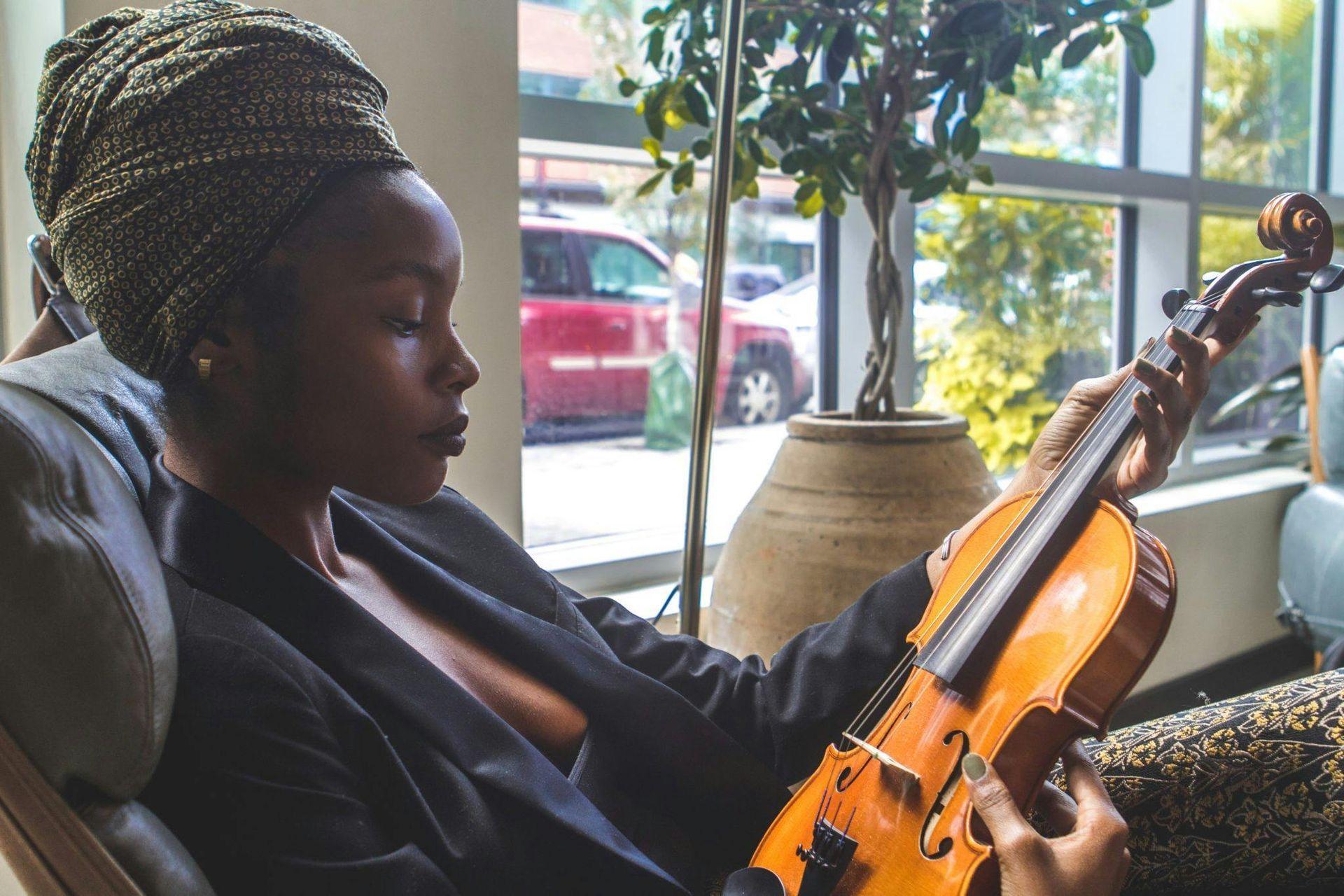 Uma mulher está sentada em uma cadeira tocando violino