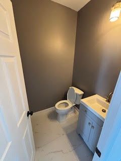 Small bathroom with gray walls, white toilet, and light blue vanity beside a sink.