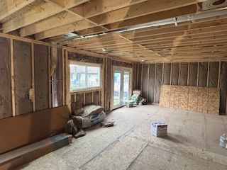 Unfinished interior of a house under construction with exposed framing, windows, and scattered materials