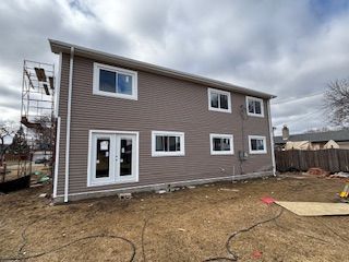 Two-story beige house under construction with a cloudy sky and bare yard