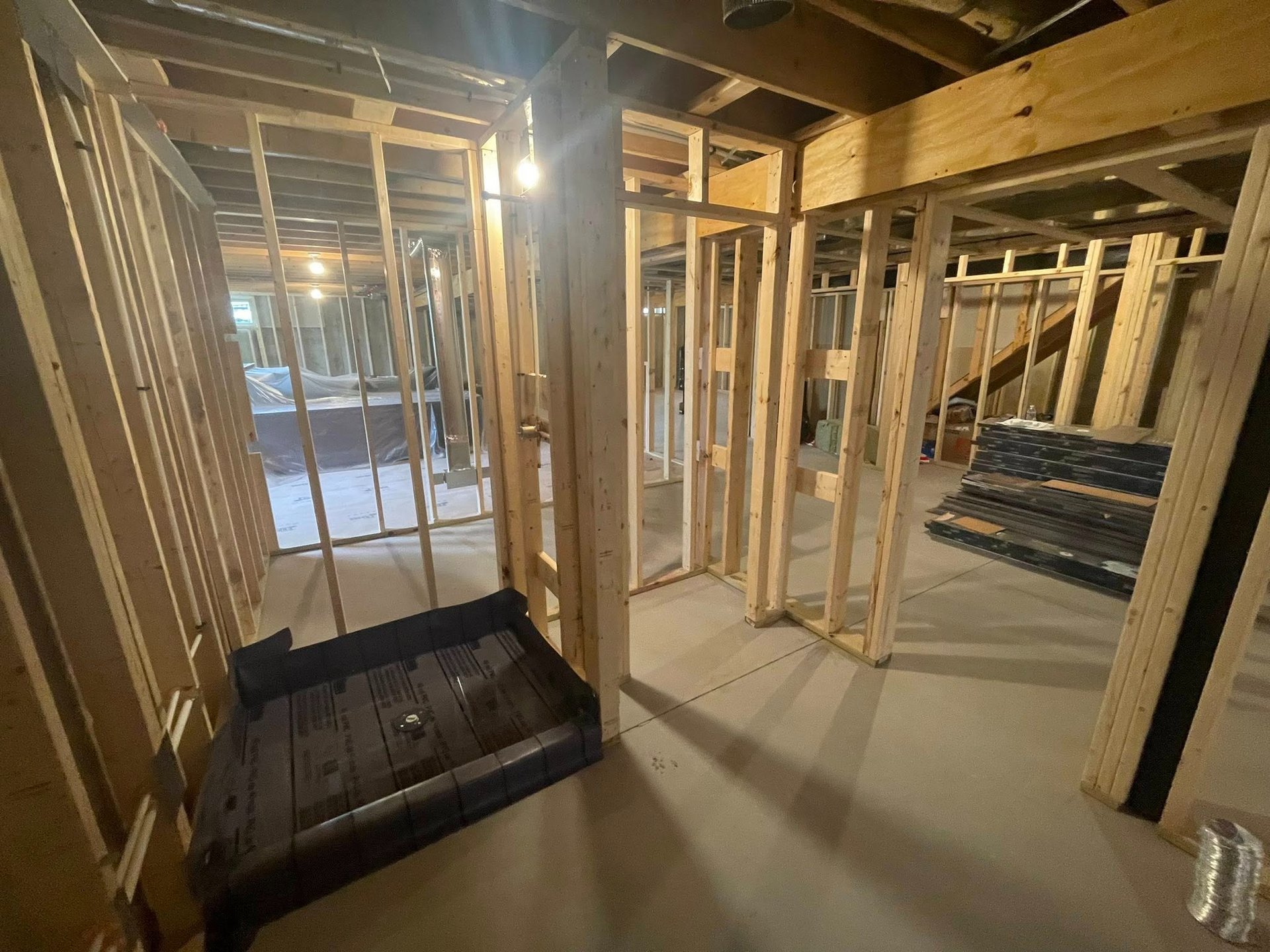 Interior of a house under construction with exposed wooden framing and a dark utility box on the floor.