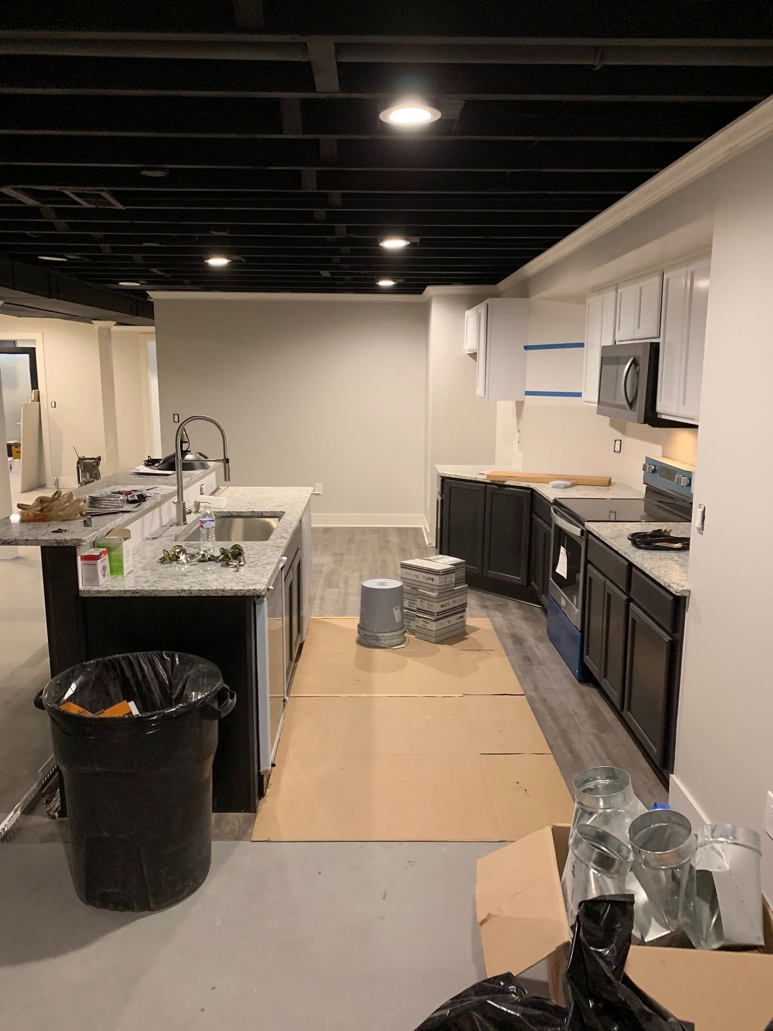 Renovated kitchen with black cabinets, island, and exposed ceiling under construction