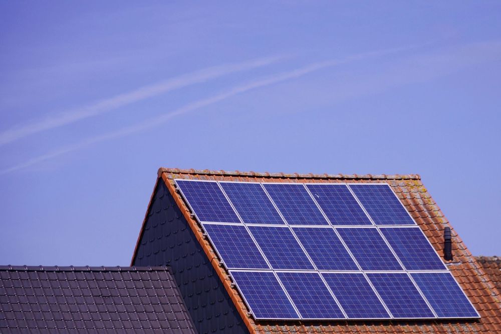 Solar panels on a roof beneath a clear blue sky.