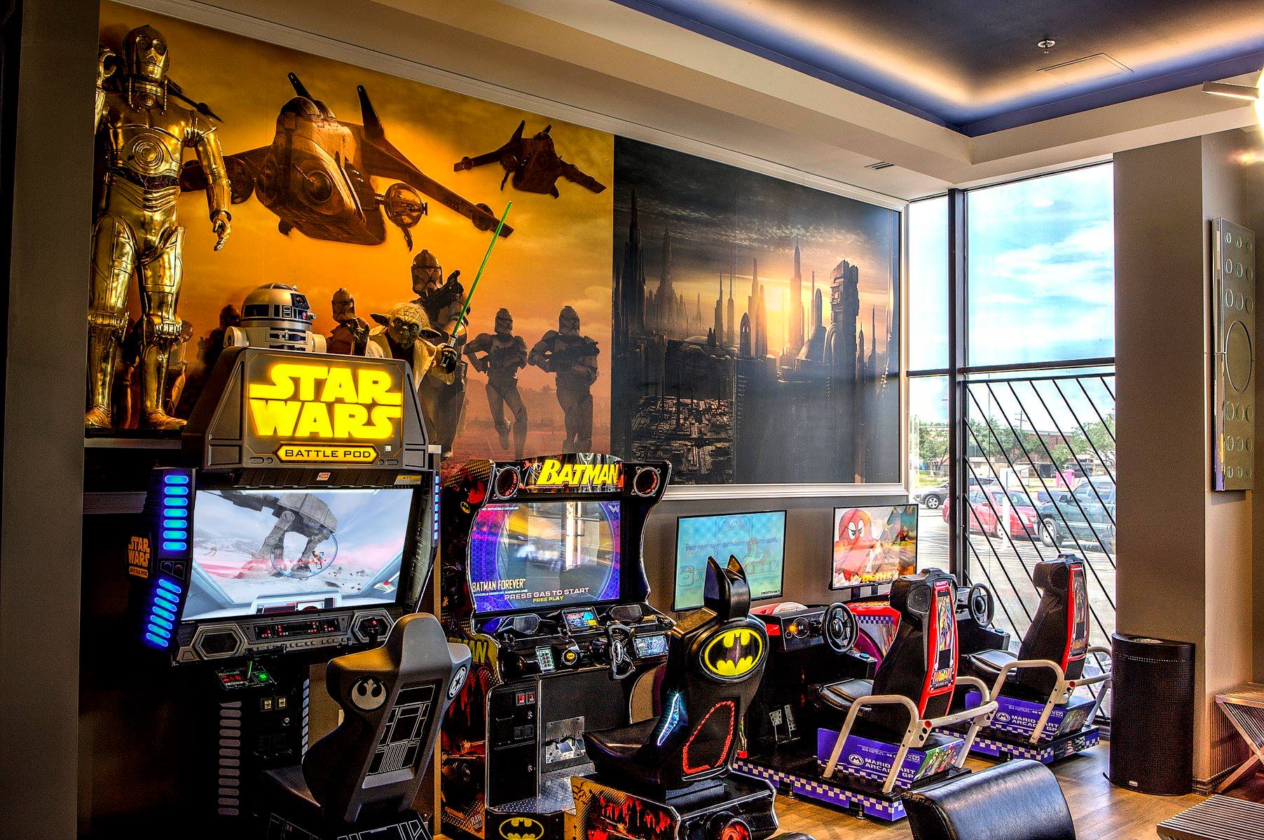 Star Wars-themed game room with arcade cabinets, neon lights, posters, and city-view window