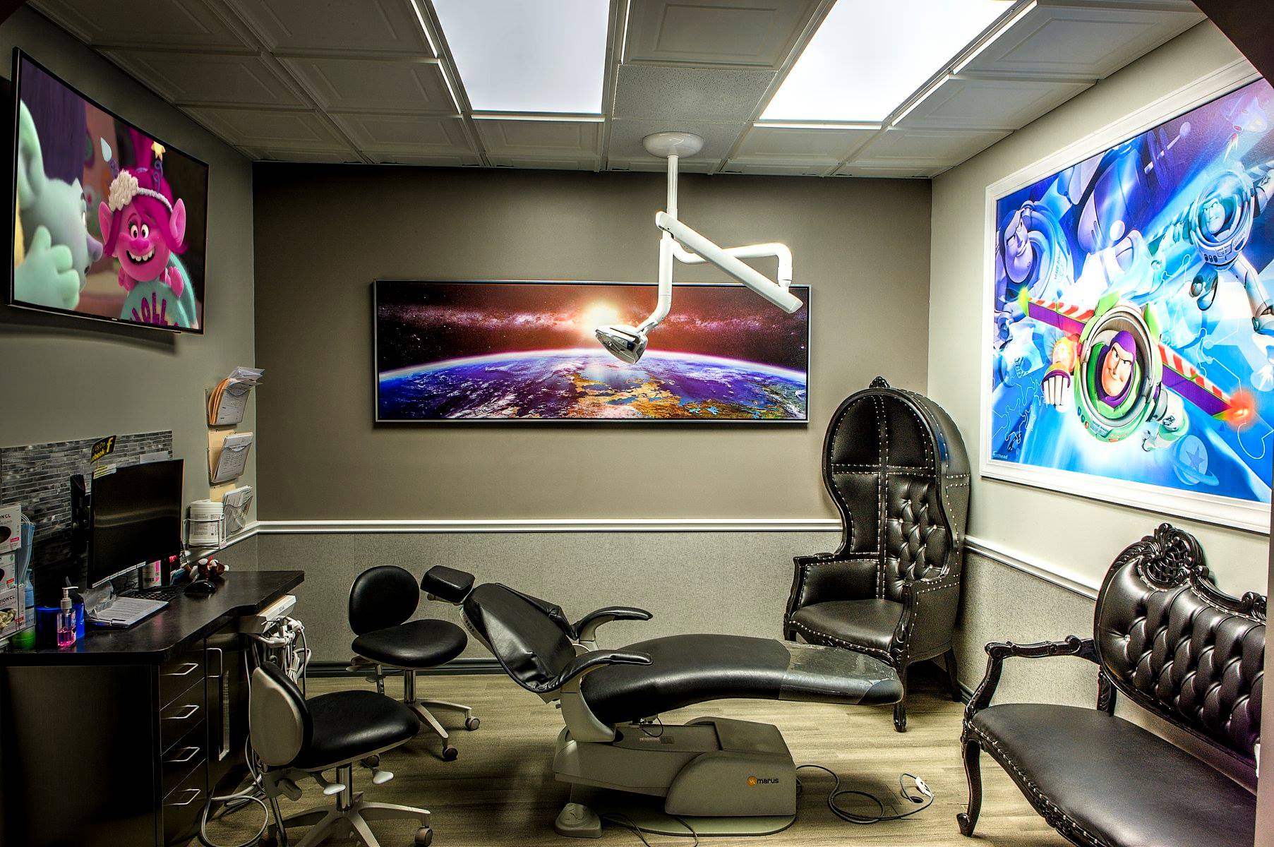 Modern gaming room with multiple screens, black chairs, and neon space-themed wall art