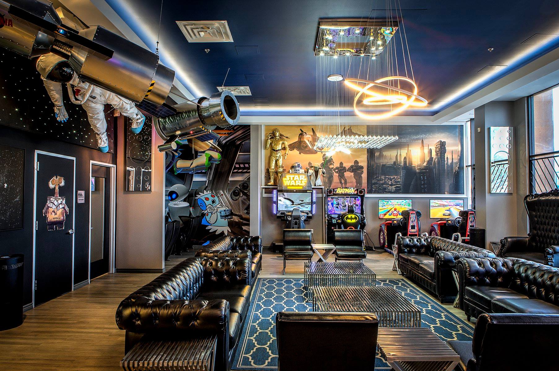 Luxury lounge with black leather seating, patterned carpet, cityscape wall art, and modern ceiling lights