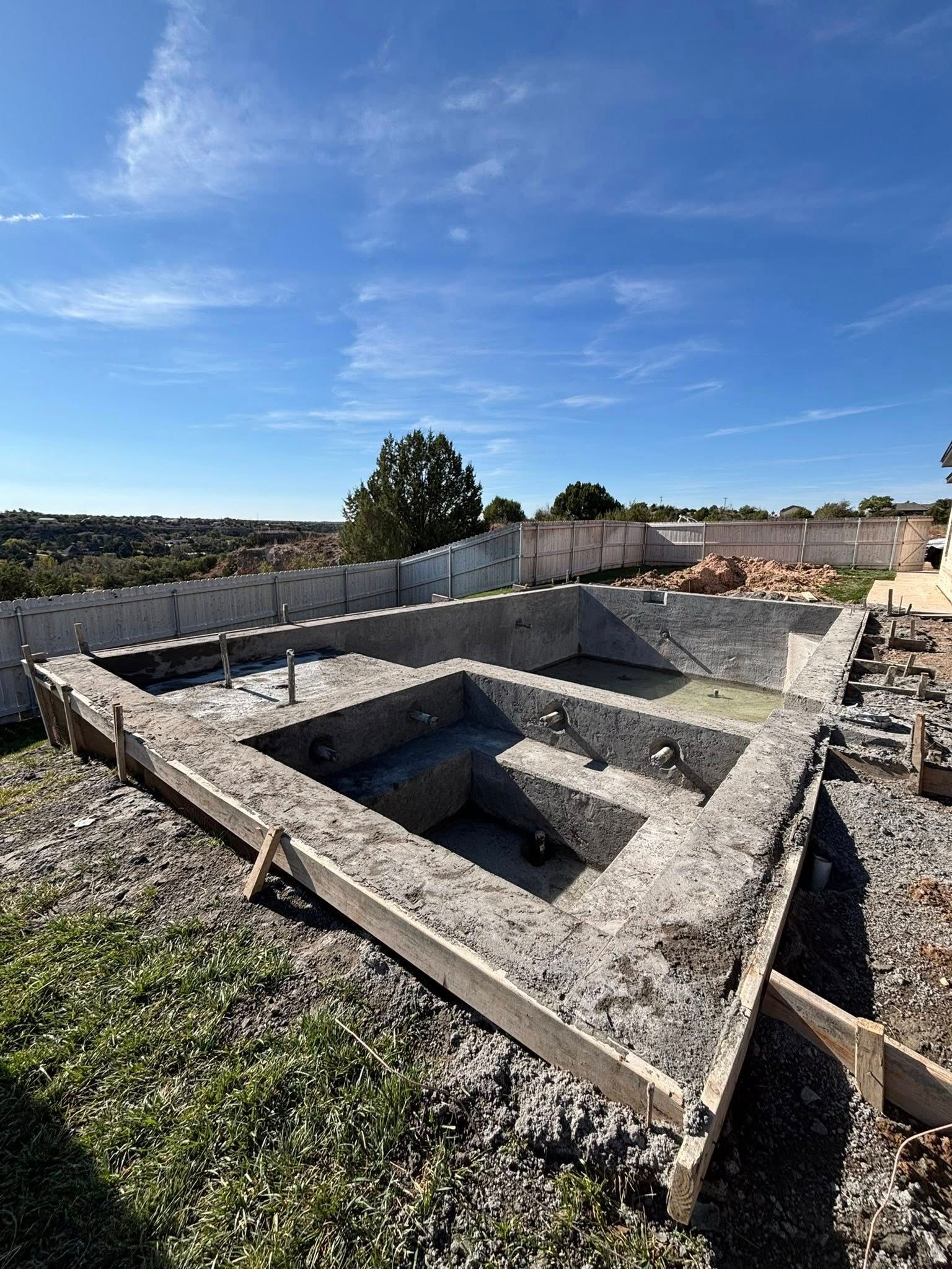 Concrete foundation forms on a construction site under a clear blue sky.