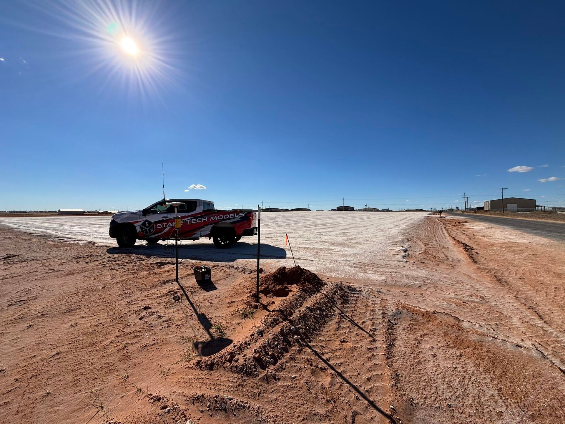 Red off-road vehicle on a snowy dirt track under a bright sun and blue sky
