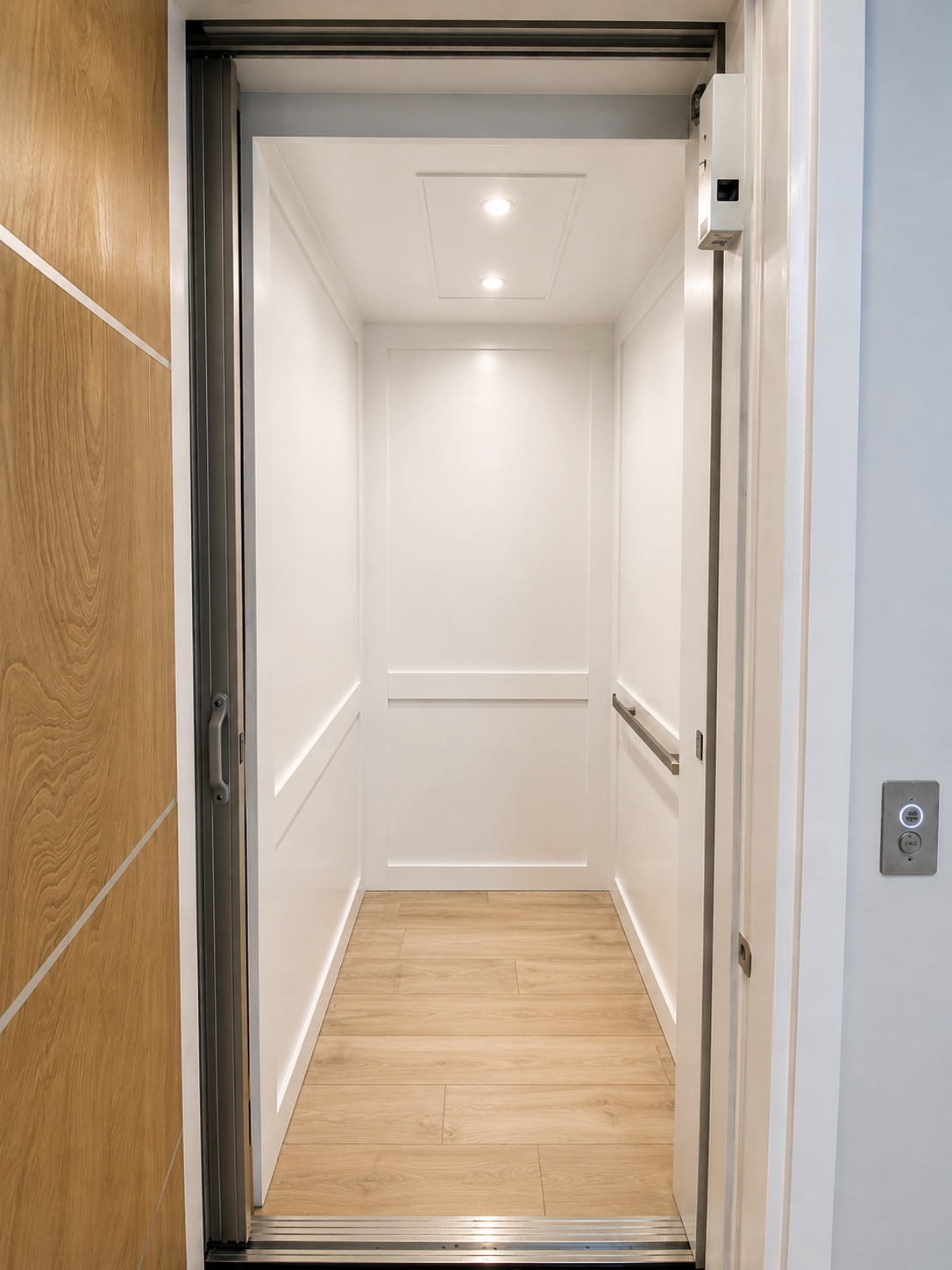 Open elevator with white interior, wood floor, and door frame visible from the hallway
